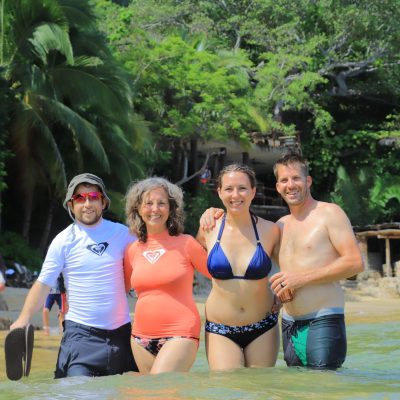Four individuals standing in shallow water, smiling and posing for the camera.